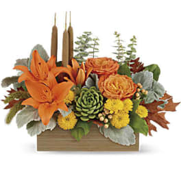 Orange lilies and roses in a wooden box with candles
