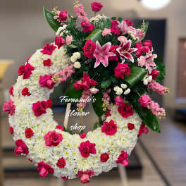 Large white chrysanthemum wreath with hot pink roses and lilies on a wooden easel