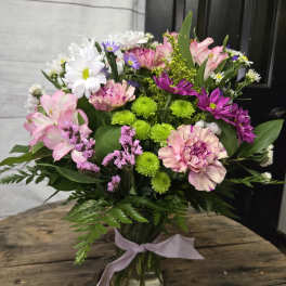 Mixed pink, white, and purple bouquet in a glass vase with a ribbon