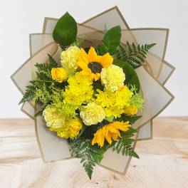 Yellow bouquet with sunflowers, roses, and carnations in tan wrap
