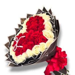 Bouquet of red and white roses wrapped in dark paper with a red ribbon