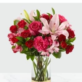 Bouquet of red roses, pink lilies, and carnations in a glass vase