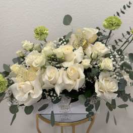 White roses and green carnations arranged with eucalyptus in a box