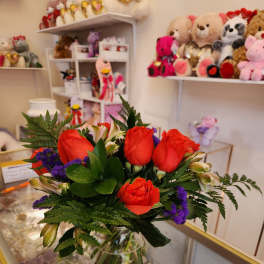 Bouquet of red roses and purple filler flowers in a glass vase