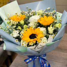 Bouquet of yellow sunflowers and white daisies wrapped in blue paper