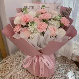 Pink and white bouquet of roses and carnations wrapped in pink paper