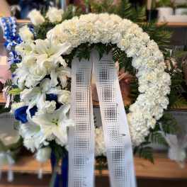 White floral funeral wreath with lilies and ribbons