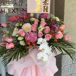 Large pink floral standing arrangement with roses and white orchids