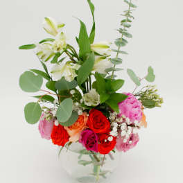 Mixed bouquet of roses and white lilies in a clear glass vase