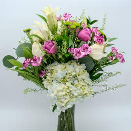 Bouquet of white lilies, pink roses, and hydrangea in a glass vase