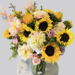 Bouquet of sunflowers, dahlias, and roses in a glass vase