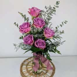 Pink roses arranged in a clear glass vase with a ribbon