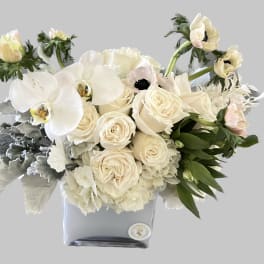 Cream roses and white orchids in a square vase