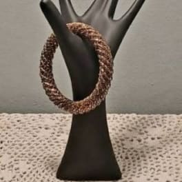 Black hand-shaped display holding a braided bracelet