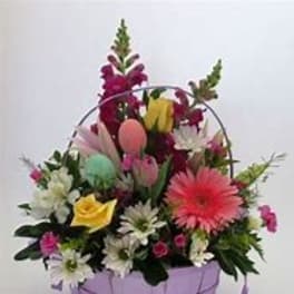 Mixed flower basket with pastel eggs in a lavender container
