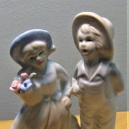 Ceramic figurine of two children holding small flower baskets