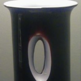Black cylindrical vase with a white oval opening detail