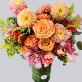 Bouquet of orange roses and pink dahlias in a green glass vase