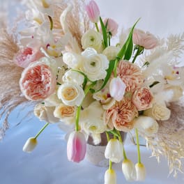 Blush and white floral arrangement with orchids and tulips in a vase