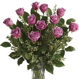 Tall arrangement of lavender roses in a clear glass vase