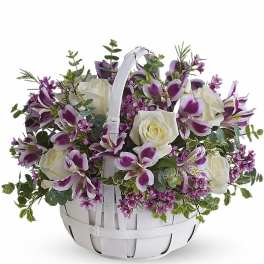 White basket of white roses and purple alstroemeria with small pink blossoms