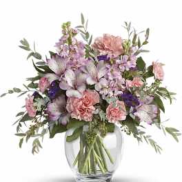 Pastel pink and lavender mixed flower arrangement in a clear round glass vase