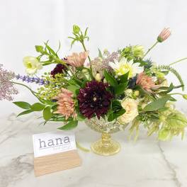 Mixed floral arrangement in a yellow glass compote vase