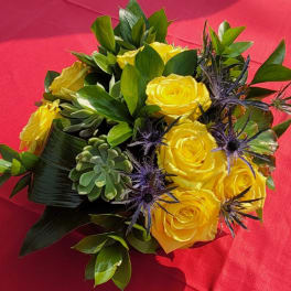 Yellow roses with purple thistle and succulents on red fabric