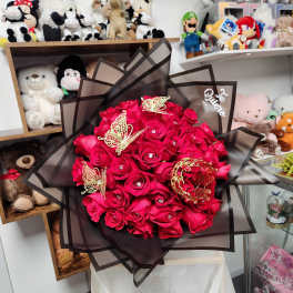 Bouquet of bright red roses wrapped in dark sheer paper with butterfly accents