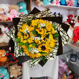 Bouquet of yellow sunflowers with white filler flowers wrapped in patterned paper