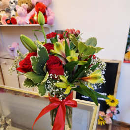 Bouquet of red roses and yellow lilies in a glass vase with a red ribbon