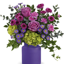 Pink and purple flower arrangement in a purple vase