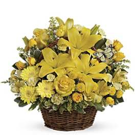 Basket arrangement of yellow lilies, roses, daisies, and mixed blooms with a small decorative butterfly accent