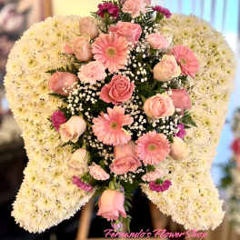 Angel wing-shaped white mum spray with pink roses and gerbera daisies on an easel
