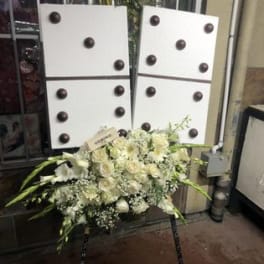 White floral standing spray on an easel with long green accents