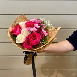 Handheld bouquet of pink and white roses with small pink daisies