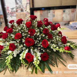 Low arrangement of red roses and white filler flowers on a table