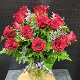 Bouquet of red roses in a glass vase with a checkered ribbon