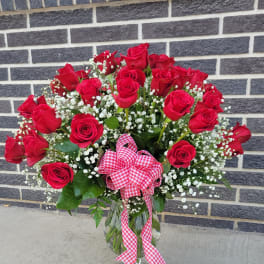 Bouquet of red roses in a glass vase with a gingham ribbon
