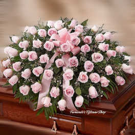 Pink rose casket spray with ribbon on a wooden casket