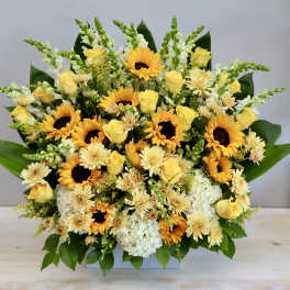 Yellow roses and sunflowers in a low rectangular arrangement