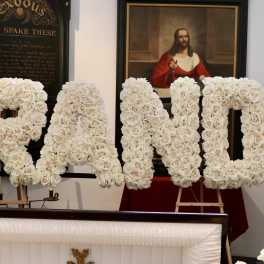 Large floral letters spelling "GRANDPA" made of white roses
