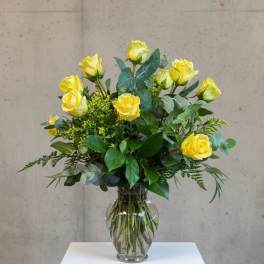 Tall arrangement of yellow roses in a clear glass vase