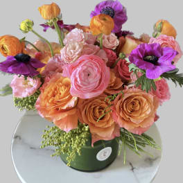 Bouquet of pink, orange, and purple flowers in a green vase