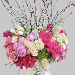 Pink and white floral arrangement in a white vase with tall branches