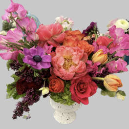 Mixed bouquet of pink, red, orange, and purple flowers in a white vase