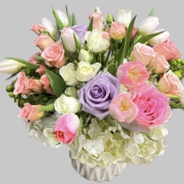 Bouquet of pink, white, and lavender roses with tulips in a vase