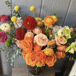 Mixed bouquet of orange and peach roses in a glass vase
