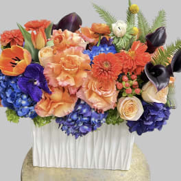 Colorful floral arrangement in a white rectangular vase