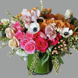 Mixed bouquet of pink, orange, and white flowers in a glass vase
